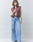 Maroon sleeveless quilted jacket by SUNCOO with cream sweater and wide-leg jeans, casual modern style.