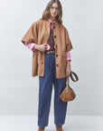 SUNCOO Ezra coat in pink over a shirt and jeans, styled with brown boots and bag, minimal studio setting.