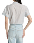 Someone is seen from behind wearing the light blue FRAME The Boardwalk Shirt with one hand on their hip, paired with light-wash jeans.