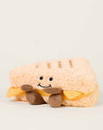 The Faire Grilled Cheese Warmies is a microwavable plush shaped like a smiling sandwich with brown limbs and yellow felt cheese, perfect for cozy comfort on any light background.