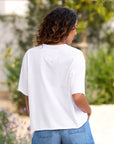 Frank & Eileen Perry Crew SS Tee in white styled with blue jeans, shown outdoors from the back on a curly-haired model.