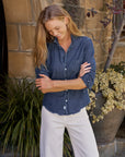 BARRY Tailored Button Up Shirt in dark blue Italian cotton denim with a raw hem worn with white pants.
