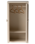 Small beige Maileg wardrobe with shelves and gold hangers, ideal for dollhouse collections at Bungalow Furniture.