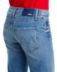 A person is shown from the back wearing Mother’s Lil Bookie Twist Skimp blue denim mid rise jeans with a five-pocket design, stitched "M" on the back pocket, belt loops, and seam details, paired with a red top.