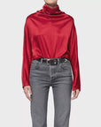 Ilaria Draped Top in long-sleeve hammered satin, styled with grey jeans and a black leather belt.