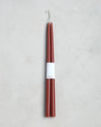 A pair of 18" taper candles by The Floral Society, bundled with a white paper label, are shown on a light gray textured surface.