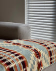 Secoya Throw in vibrant mint with a geometric southwestern pattern, draped over a gray sofa from Bungalow Furniture.