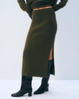 Olive green ribbed cashmere side-slit skirt worn with black knee-high boots.