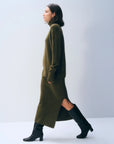 Olive green ribbed turtleneck and White + Warren cashmere skirt with side slit, paired with black knee-high boots.