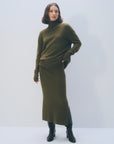 Olive green ribbed turtleneck sweater and White + Warren cashmere skirt worn with black boots.