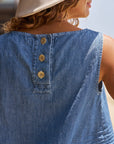 A person with curly hair and a beige hat wears the Frank & Eileen Shell Tank—an indigo, sleeveless top featuring three horn buttons on the upper back. The image emphasizes the tank's distinctive details.