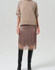 Citizens Of Humanity lace trimmed beige skirt styled with a turtleneck and black knee-high boots.