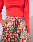 Whisper Pant floral skirt with elastic waistband and relaxed fit, paired with a red long-sleeved shirt.