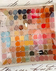 The Watercolor Artist's Palette Decoupage Glass Tray by Faire features a vintage square grid of vibrant watercolor swatches atop handwritten script—ideal inspiration for your next handmade project.