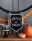 Pumpkins and a black cake on a bench with festive Halloween decor and Faire Trick or Treat banner, Bungalow Furniture.