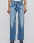 A person wearing Moussy Asheville Remake Flare high-waisted, light blue wide-leg jeans with a button fly and raw hem, paired with a white top and brown pointed-toe shoes, shown waist down against a plain background.
