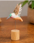 Hand-painted brown carved hummingbird on wire stand by Faire, displayed on a polished wood surface.