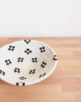 Small black sisal Maraba bowl by Faire with geometric weaving, shown on light wood against a white wall.