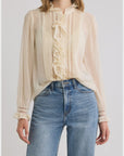 Sheer chiffon DOEN Magdeleine top with lace and ruffled collar, styled with blue high-waisted jeans.