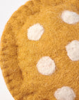 A close-up of Faire's Mushroom Critter—a round, brown felt piece with stitched edges and white spots—perfect whimsical toadstool mushroom decor or cozy cottagecore accent, set against a plain light background.