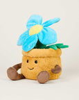 The Blue Flower Pot Warmies by Faire is a microwavable plush shaped like a smiling brown flowerpot with arms, legs, and a large blue and yellow flower, offering cozy comfort against a plain light background.