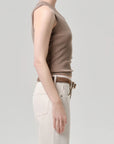 A person stands in profile against a plain background, wearing the Citizens Of Humanity/AGOLDE nova tank—a taupe ribbed top with a scoop neckline—paired with light pants and a brown belt. Their face is not visible.