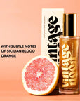 A bottle of Faire Shimmer Body Oil stands next to its box with a halved blood orange. Text reads: "With subtle notes of Sicilian blood orange and antioxidant-rich, shimmering body oil" on a peach background.