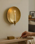 Brass wall candle sconce from Bungalow Furniture on mantel, lit with a match from a hand-held matchbox.