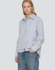 Oversized light blue Zayna button down with layered striped hem and cuffs, worn with blue jeans.