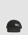 The Clare Vivier Baseball Hat - Comme Ci Comme Ca is a black cotton, adjustable hat with white embroidered "COMME CI COMME ÇA" text on the front, sliding metal closure, and one-size-fits-most fit. Shown on a plain light gray background.