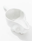 The Gravy Boat No. 151 by Montes Doggett is a white, glossy handmade ceramic piece with a smooth finish and a handle. Crafted from high-fired ceramic, it features a wide spout for easy pouring and stands out beautifully against its plain white background. The design embodies simplicity and modernity, true to the style of Montes Doggett ceramics.