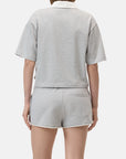 A person is shown from behind wearing the CLOSED Cropped Rugby Shirt in light gray with a white collar, paired with matching shorts against a plain white background.