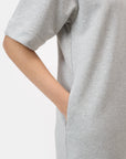 A person models the CLOSED Felpa Dress in light grey—made in Portugal from 100% cotton Felpa fabric—with a short-sleeve, shoulder to mid-thigh cut, and a hand in the side pocket, against a plain white background.