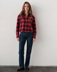 Cissa The FIELD Shirt in Redwood plaid styled with blue jeans, brown shoes, white wall backdrop.