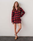 The MINI Skirt in a red plaid pattern, styled with tan loafers, modeled by Cissa against a white wall.