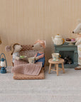 Two Maileg mice lounge on the Maileg Sofa Bed with tea cups and a pink blanket, while a third mouse serves tea and pastries by a blue cabinet. The charming scene also includes polka-dot accents, a lamp, and a small lantern.