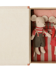 Maileg Christmas twin mice in winter clothing tucked in a cardboard box bed with a red-striped blanket.