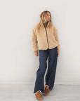 Kerri Rosenthal Coze Magoze jacket in tan with Imperfect Heart elbow patches, worn with wide-leg jeans and brown slip-ons.
