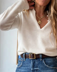 Cream Femme ruffle henley sweater tucked into blue jeans with a brown leather belt.