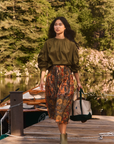 Fallon Skirt by Hunter Bell NYC styled for a lakeside stroll, paired with a casual tote on a dock with trees in view.