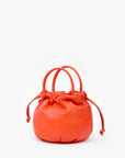 Round orange nappa leather bag with top handle and drawstring, Clare Vivier Emma style, on white background.