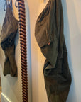 Olive green cashmere-blend corduroy baggy drawcord pants hanging on a twisted wooden pole.