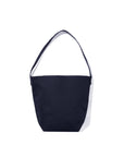 The Uma by Kule is a simple, dark navy blue cotton canvas bucket bag with a single shoulder strap, shown on a white background.