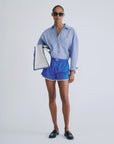 Blue shorts by Love Stories and striped shirt styled with sunglasses and a white bag against a plain background.