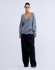Love Stories RACHEL jumper in grey worn over a pale blue lace camisole with wide-leg dark trousers.