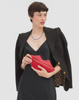 Clare Vivier Lips Flat Clutch in red with gold zipper held by model.