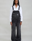 Denimist Slouch Bib Overall in washed black corduroy with adjustable straps worn over a white collared shirt.