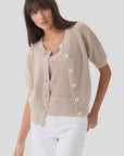 Mia Fratino Cashmere Rue Relaxed Cardigan and scoop-neck top in beige worn with white pants.