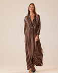 Brown and black striped maxi dress with v-neck by Natalie Martin, modeled against a light background.