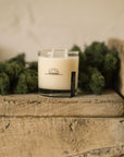 Faire Oak Moss candle in a clear glass jar on a rustic wooden shelf with moss accents.